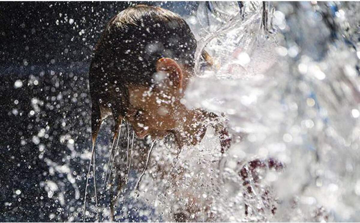 Un xiquet es refresca a una font per a poder aguantar la calor