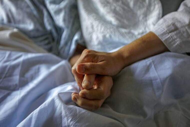 Dos persones agafades de la mà en un llit d'hospital