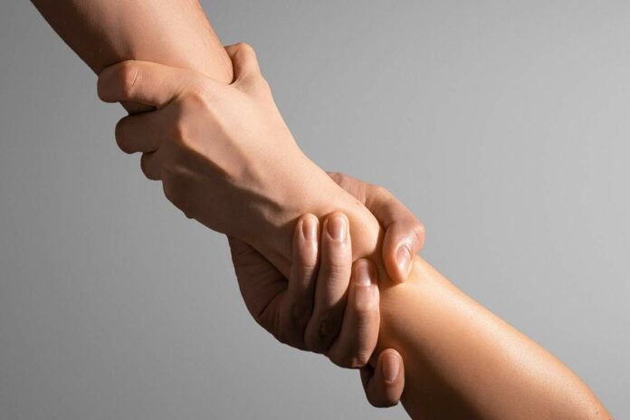 Una mà agafant una altra per ajudar-la en un moment complicat