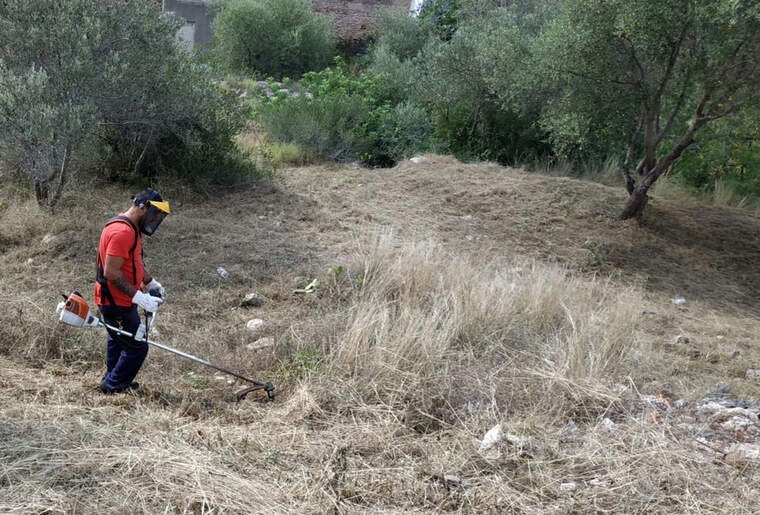 Un treballador tallant la mala herba