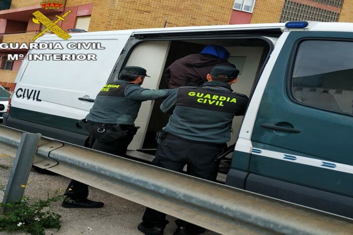 Dos agents de la Guardia Civil ficant dins d'un furgó a un detingut