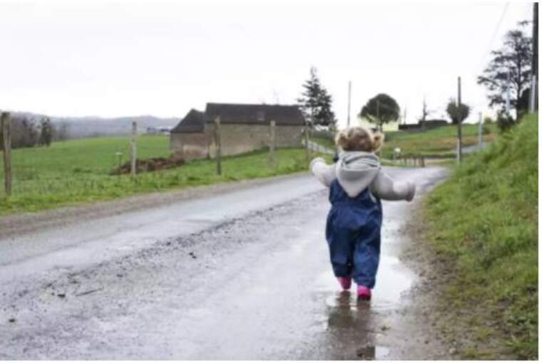 Una xiqueta caminant per un camí entollat