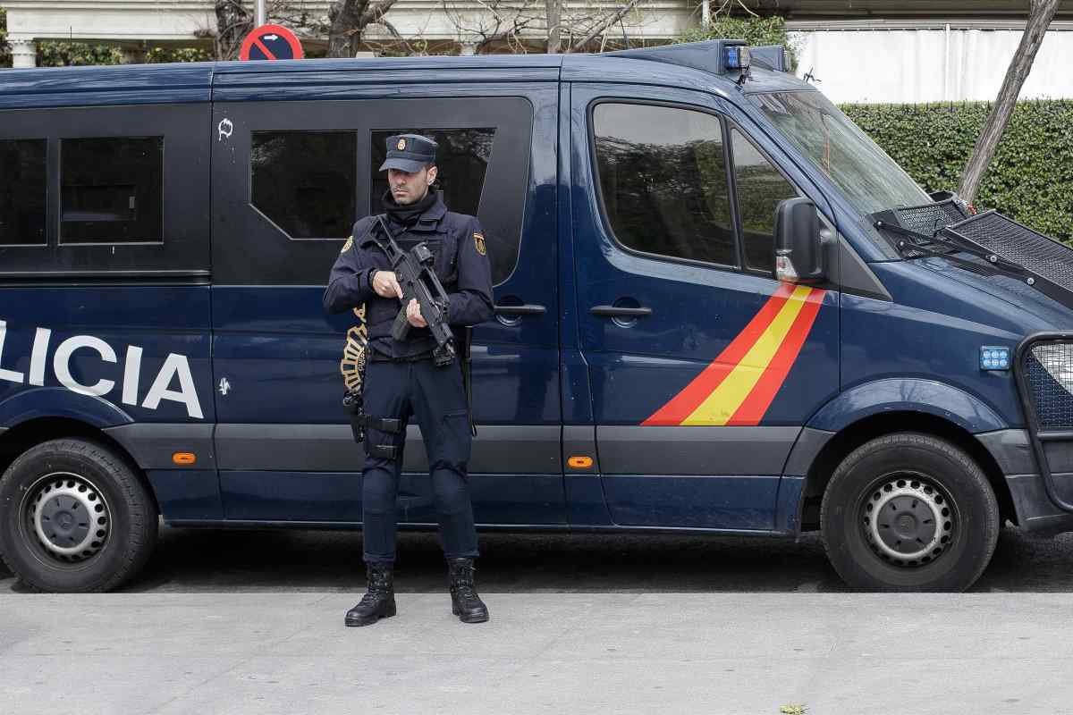 Un agent de la Policia Nacional, arma en mà, davant una furgoneta del CNP.