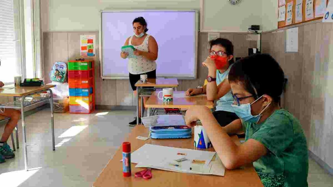 Siversos alumnes amb mascareta en una aula fent activitats