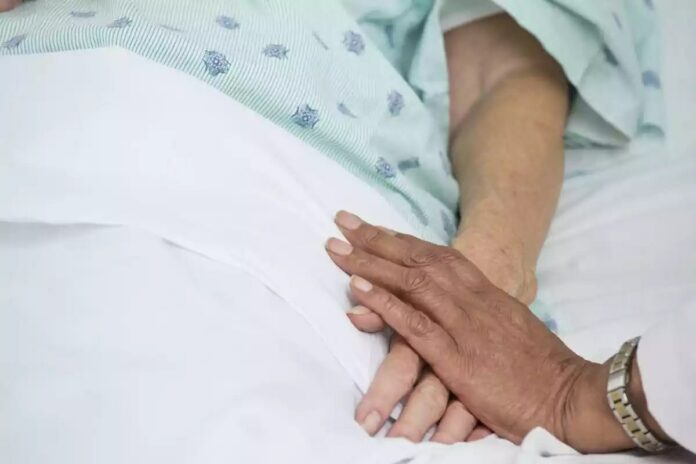 Imatge d'una persona donant la mà a una altra que es troba ingressada a l'hospital