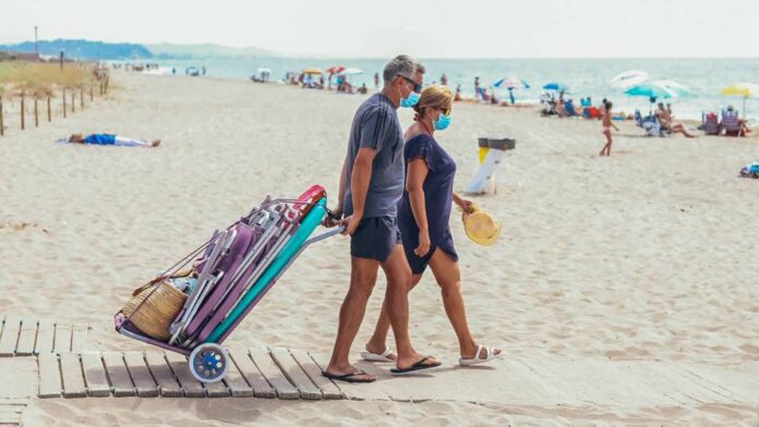 Una dona i un home amb mascaretes entrant en una platja