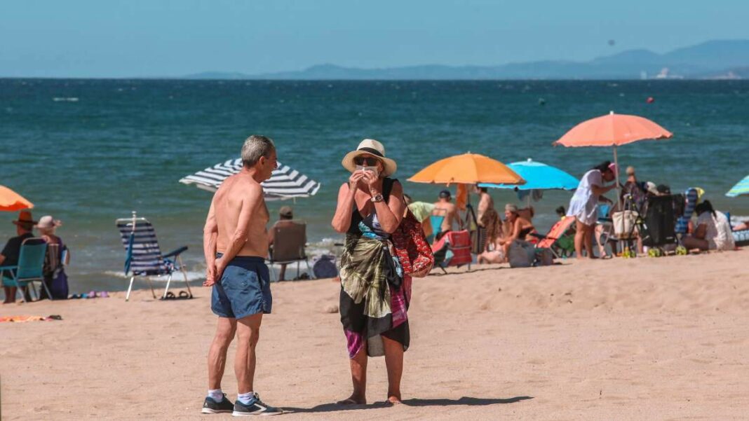 Imatge d'una turista posant-se bé la mascareta a la platja de Salou, l'estiu del 2020
