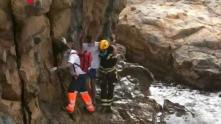 Un sanitario y un bombero socorren al joven en la base del acantilado