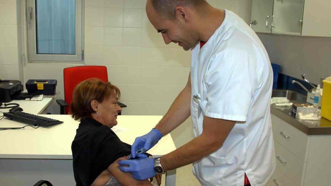 Un infermer d'un CAP injectant la vacuna de la grip a una pacient.