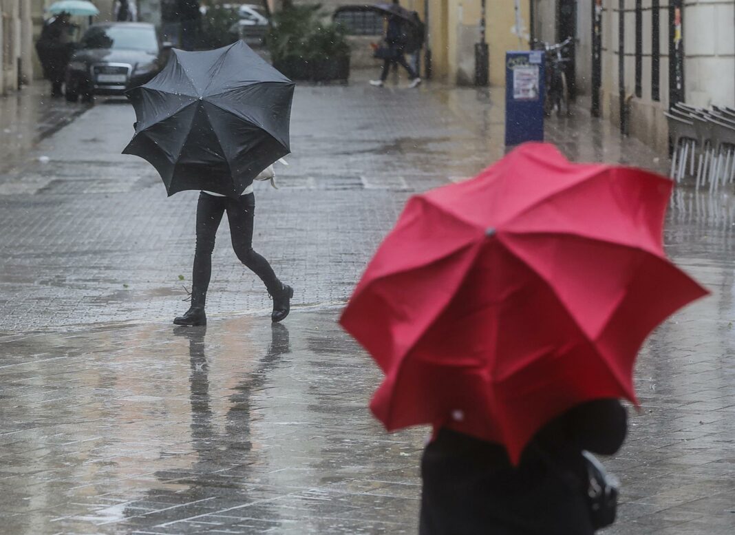 Dos persones sostenen paraigües com a conseqüència de la pluja. a 6 de febrer de 2023, a València.