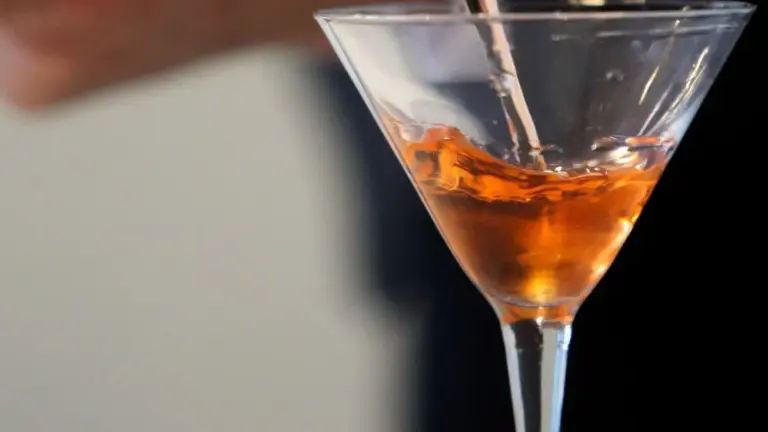 Barman elaborant un còctel en un certamen, amb ingredients i recipients sobre la barra.